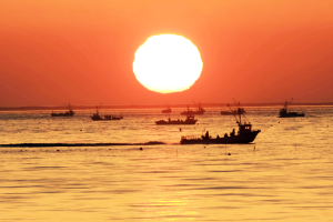 サロマ湖に浮かぶ漁船の奥に大きな太陽