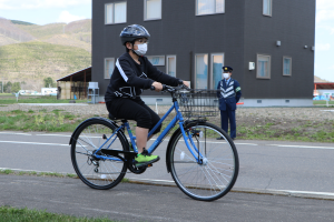 自転車に乗る児童と見守る交通安全指導員