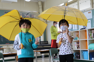 黄色い傘を嬉しそうに開く児童の様子