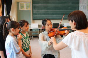 バイオリンの体験をする児童